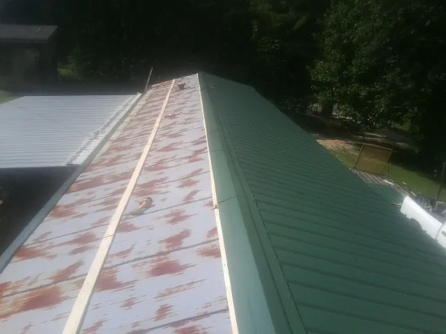 Old rusted panels beside newly installed green metal roofing — Wind Damage Roof Repair by Roofing Brothers in Wheatland