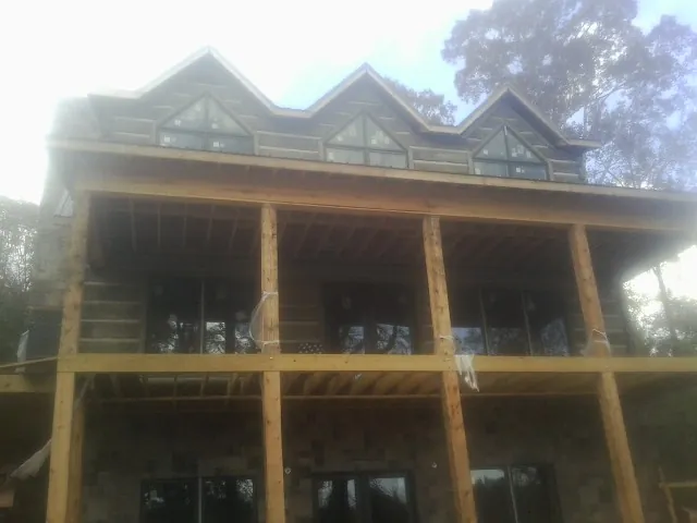Dormers and porch framing on a large log home under construction — Roof Coating work by our crew in Wheatland